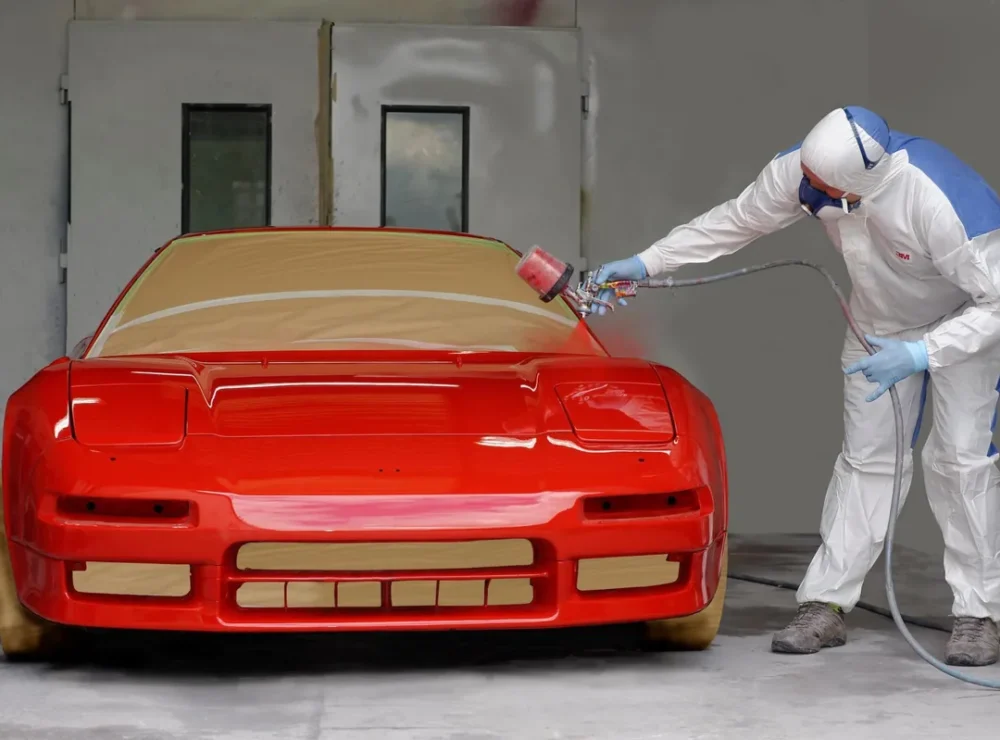 Painter spraying a red car in the paint booth