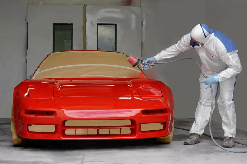 Painter spraying a red car in the paint booth