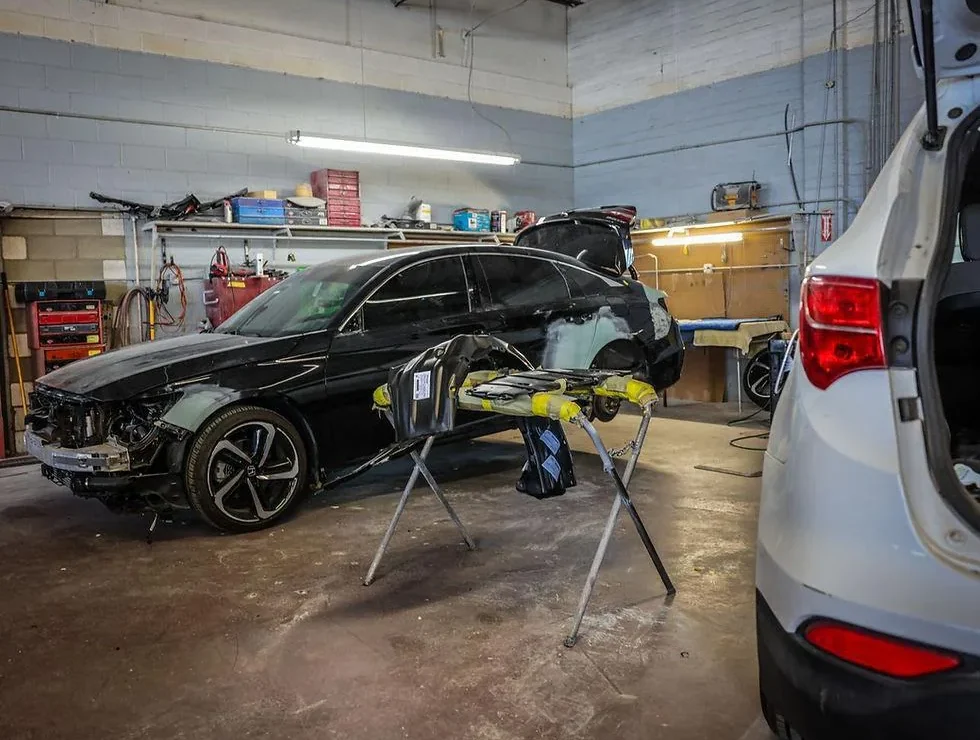 Damaged black sedan on a frame bench in the collision repair bay