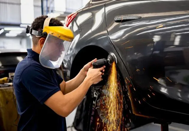 Damaged black sedan on a frame bench in the collision repair bay