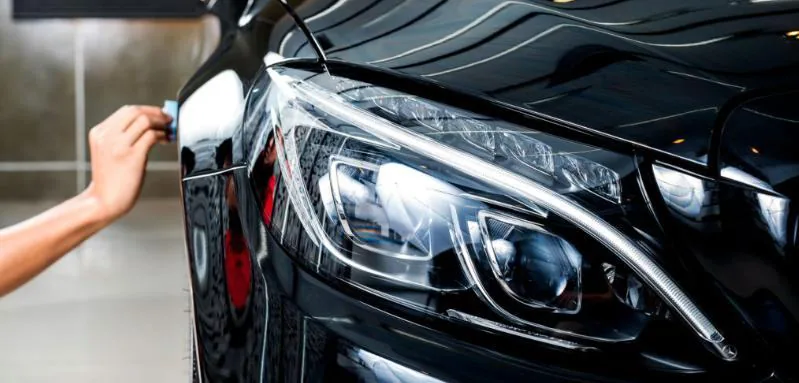 Technician polishing a cloudy car headlight