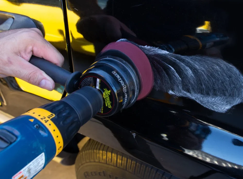 Polisher removing scratches from black car paint